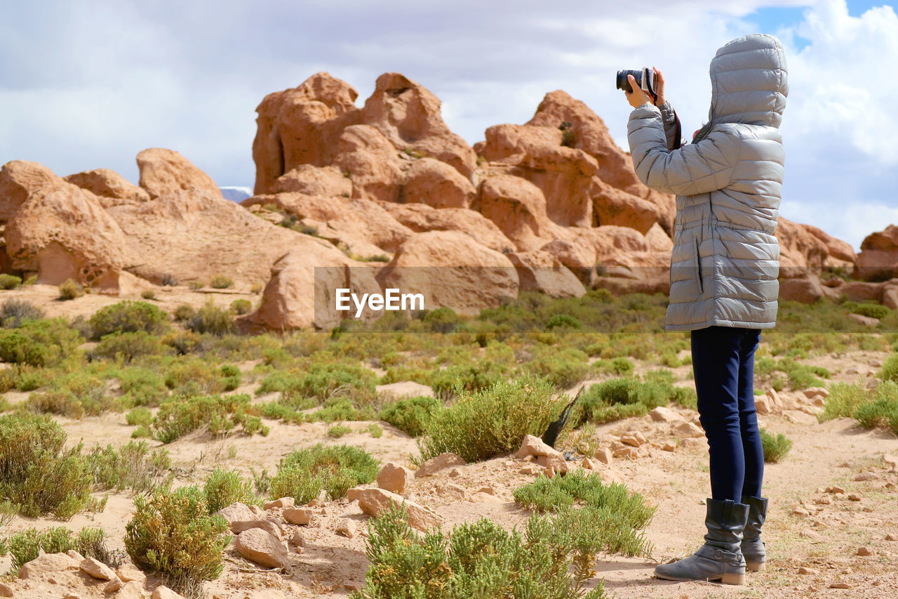 Female shooting photos of landscape with plenty of rock formations in siloli desert, bolivia