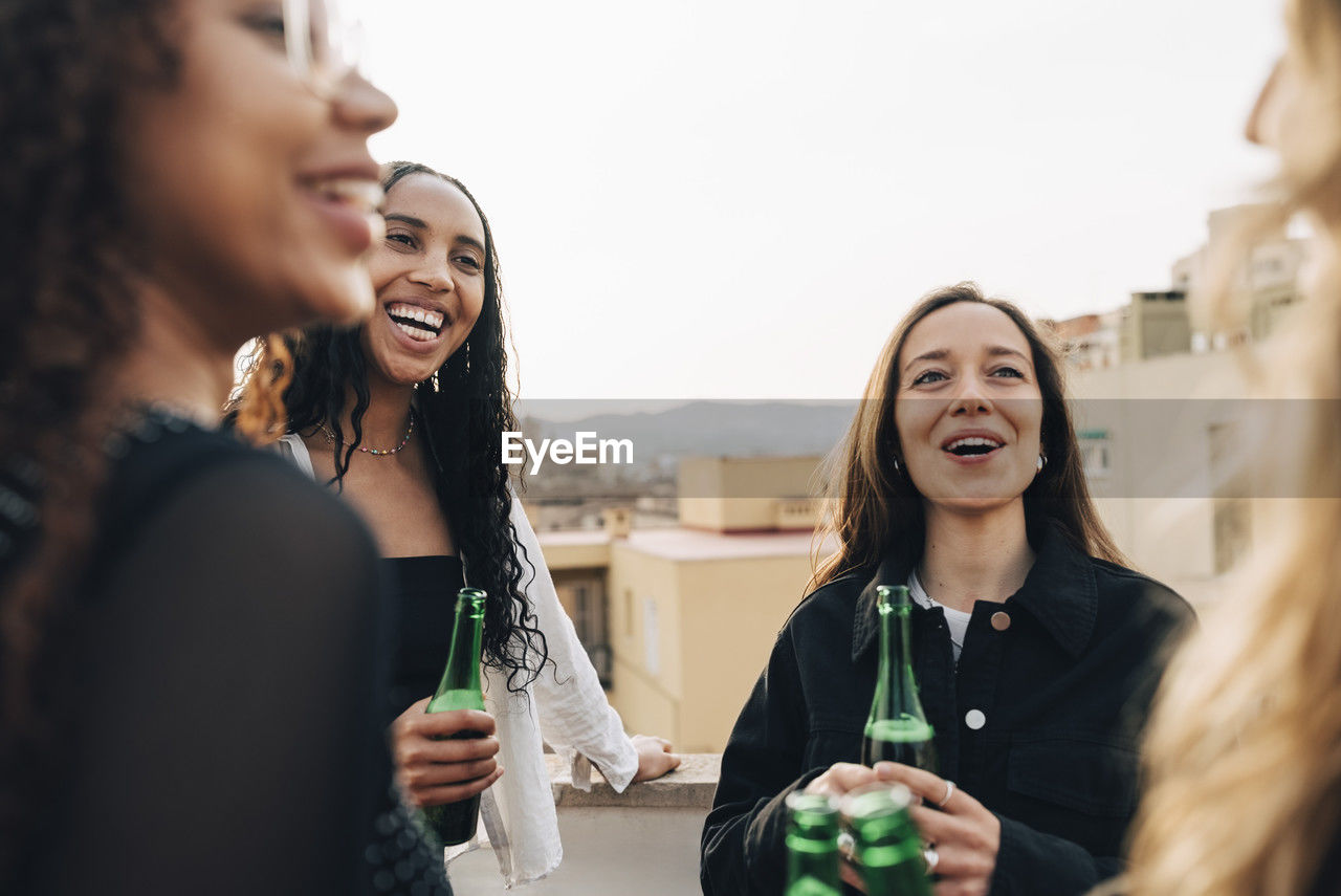 Carefree women having beer and enjoying with each other at rooftop party