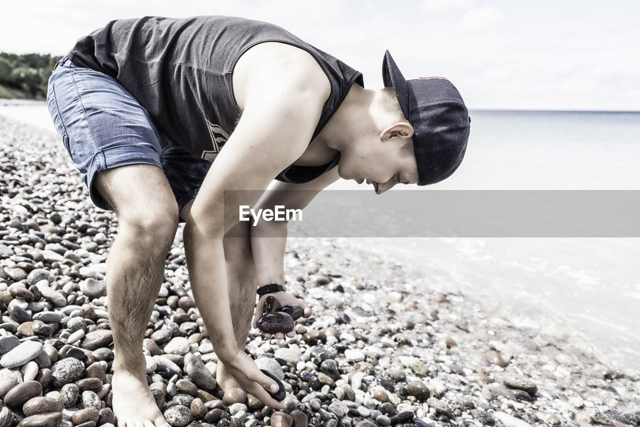 Man collecting pebbles on shore