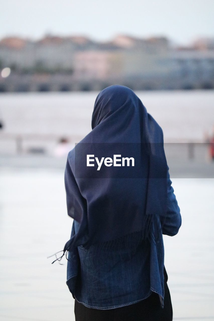 Rear view of woman standing by river