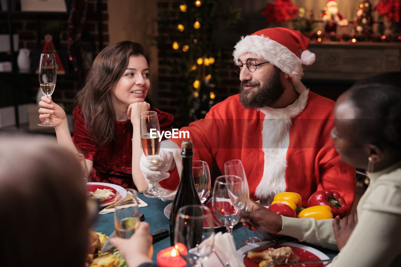 smiling friends toasting wineglasses on table