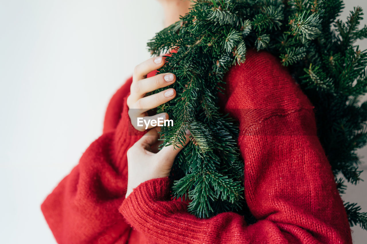 A natural spruce wreath hangs on the shoulder of a woman 