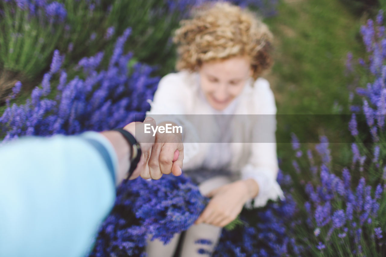 Cropped image of person holding woman hand at lavender field