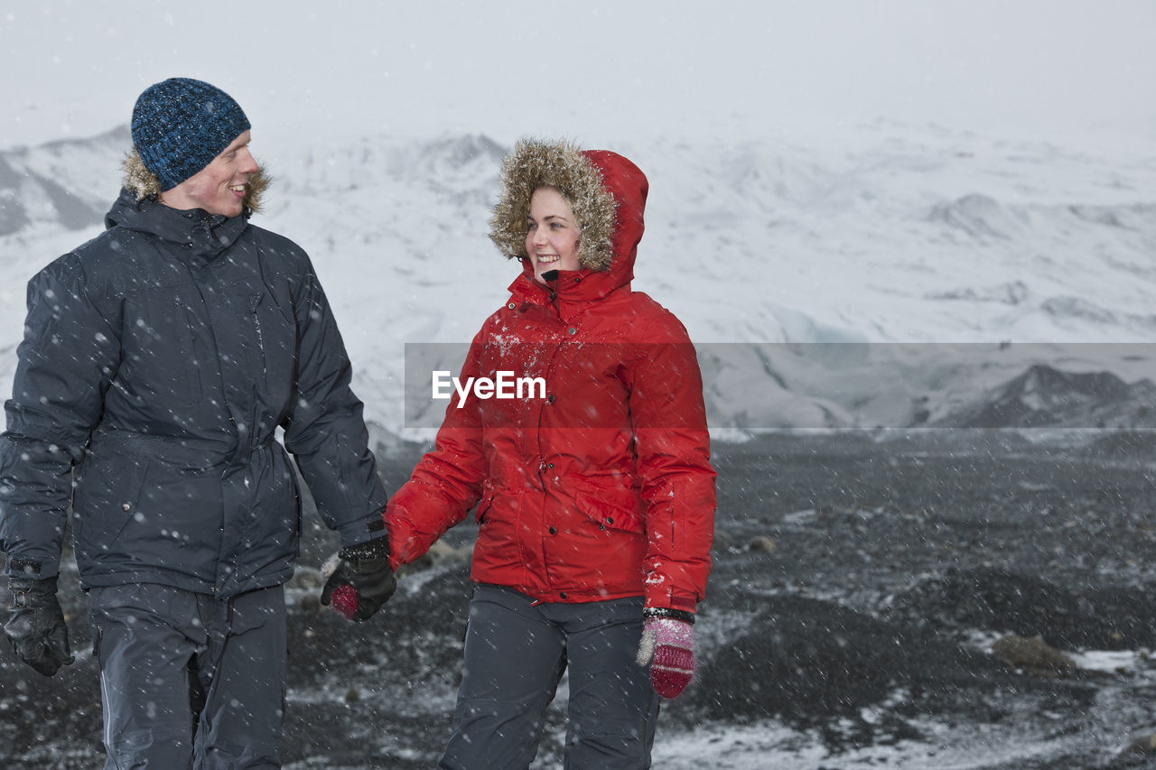 Young couple walking through snowstorm in iceland