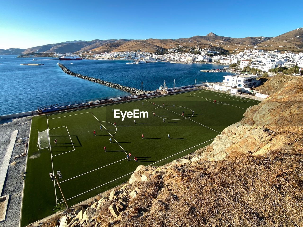 An aerial view of tinos football ground as a youth football match takes place, chora, tinos