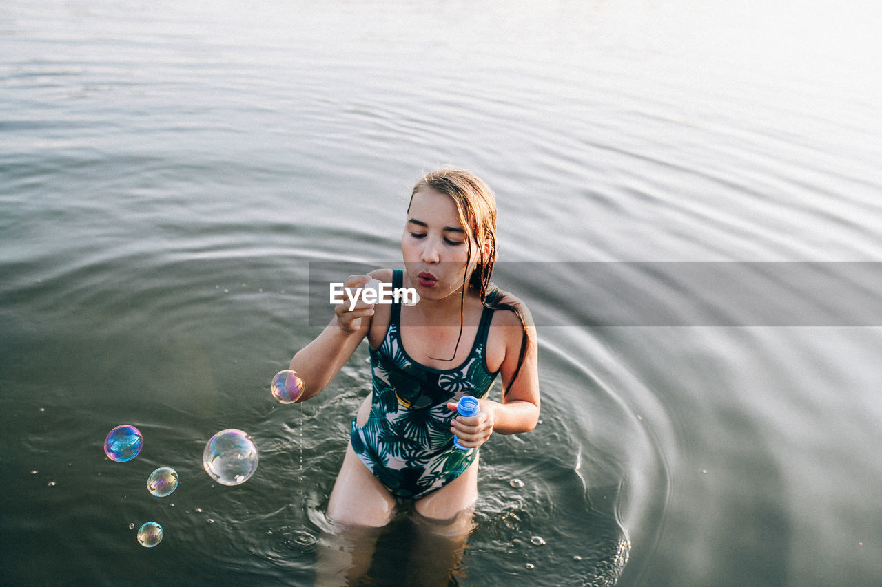 High angle view of girl blowing bubbles in lake