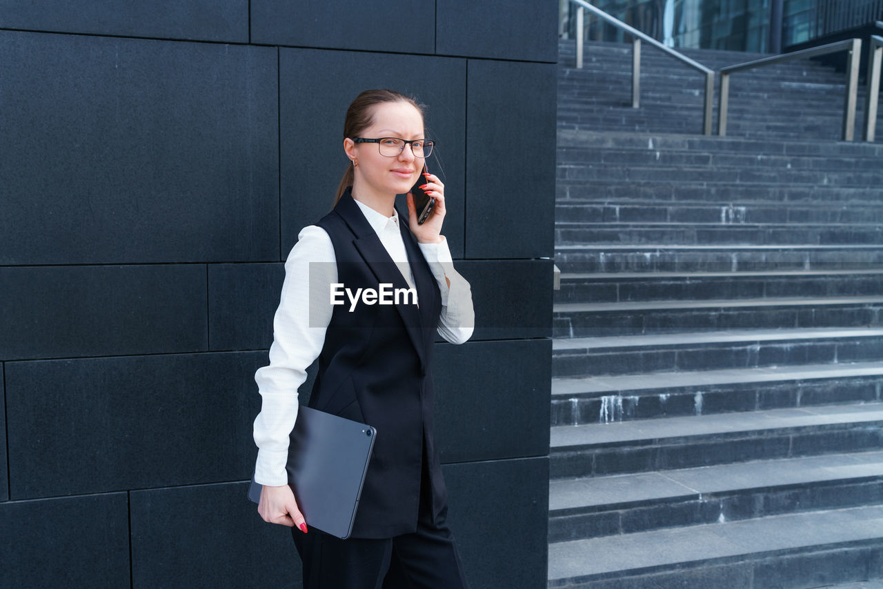 Happy woman in trendy glasses and business suit is focused on getting