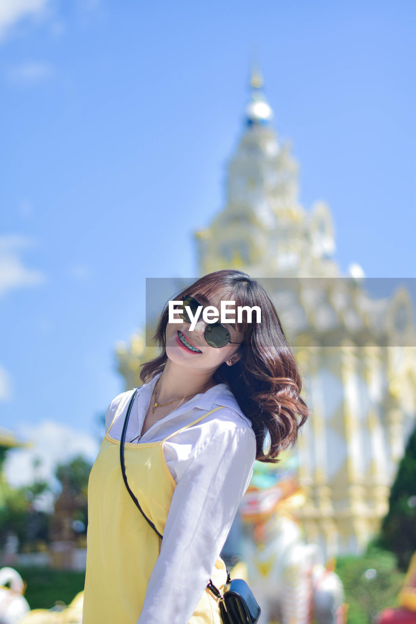 Portrait of young woman wearing sunglasses while standing outdoors