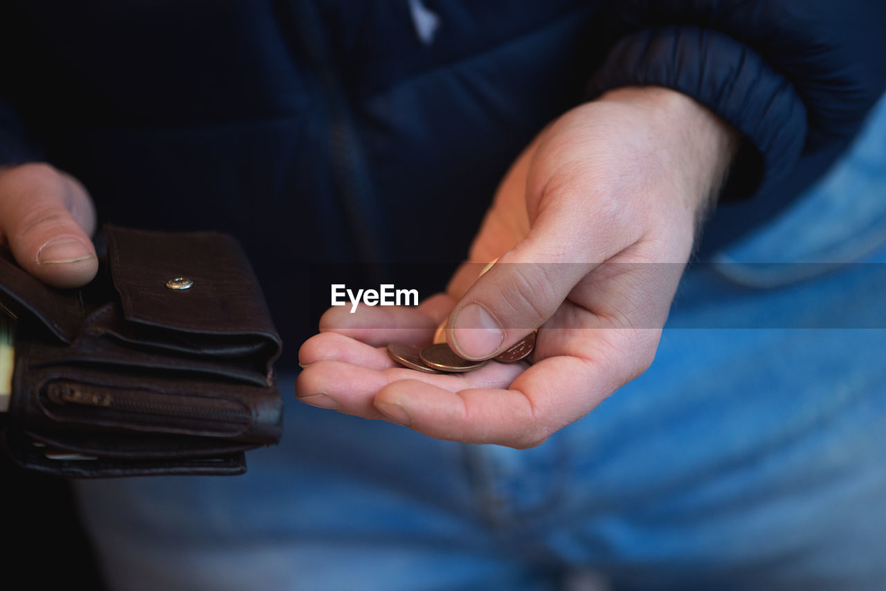 Midsection of man putting coins in wallet