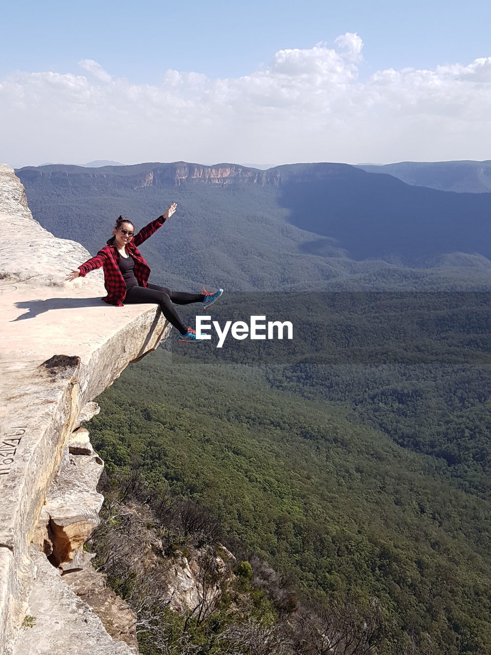 Woman sitting on mountain against sky