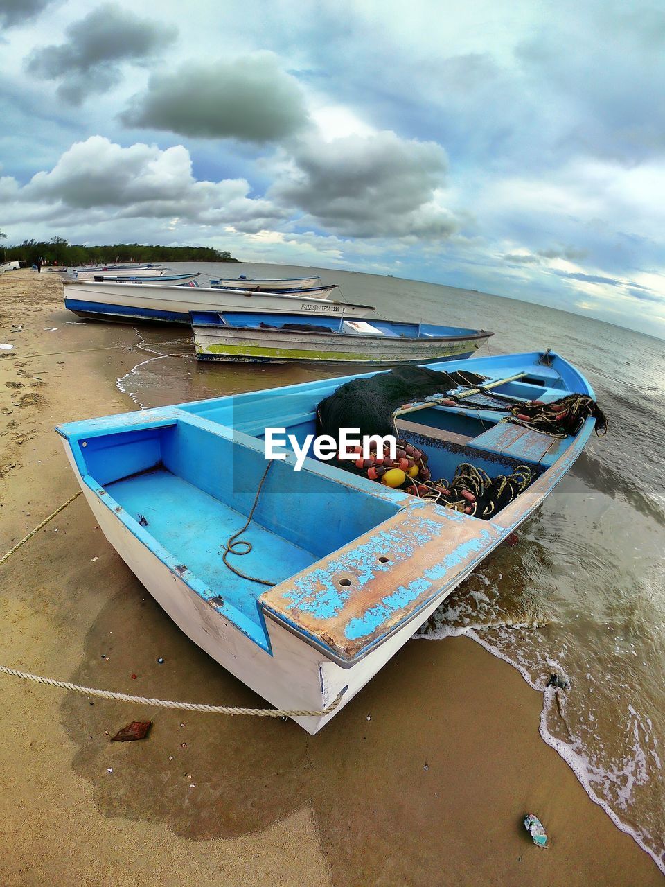 BOATS MOORED ON SHORE AGAINST SKY