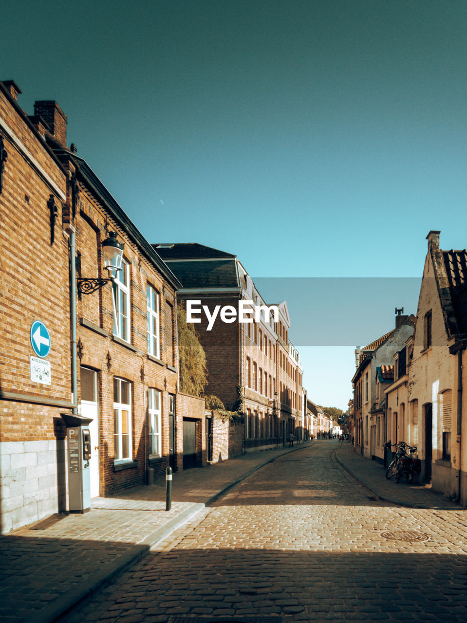 Cobbled street amidst medieval houses against clear blue sky