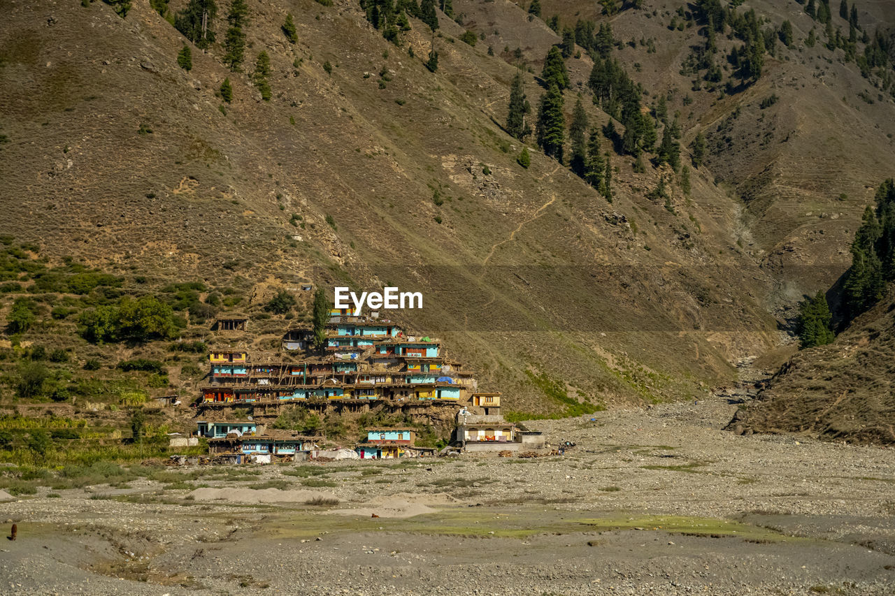 HIGH ANGLE VIEW OF VEHICLES ON ROAD ALONG BUILDINGS