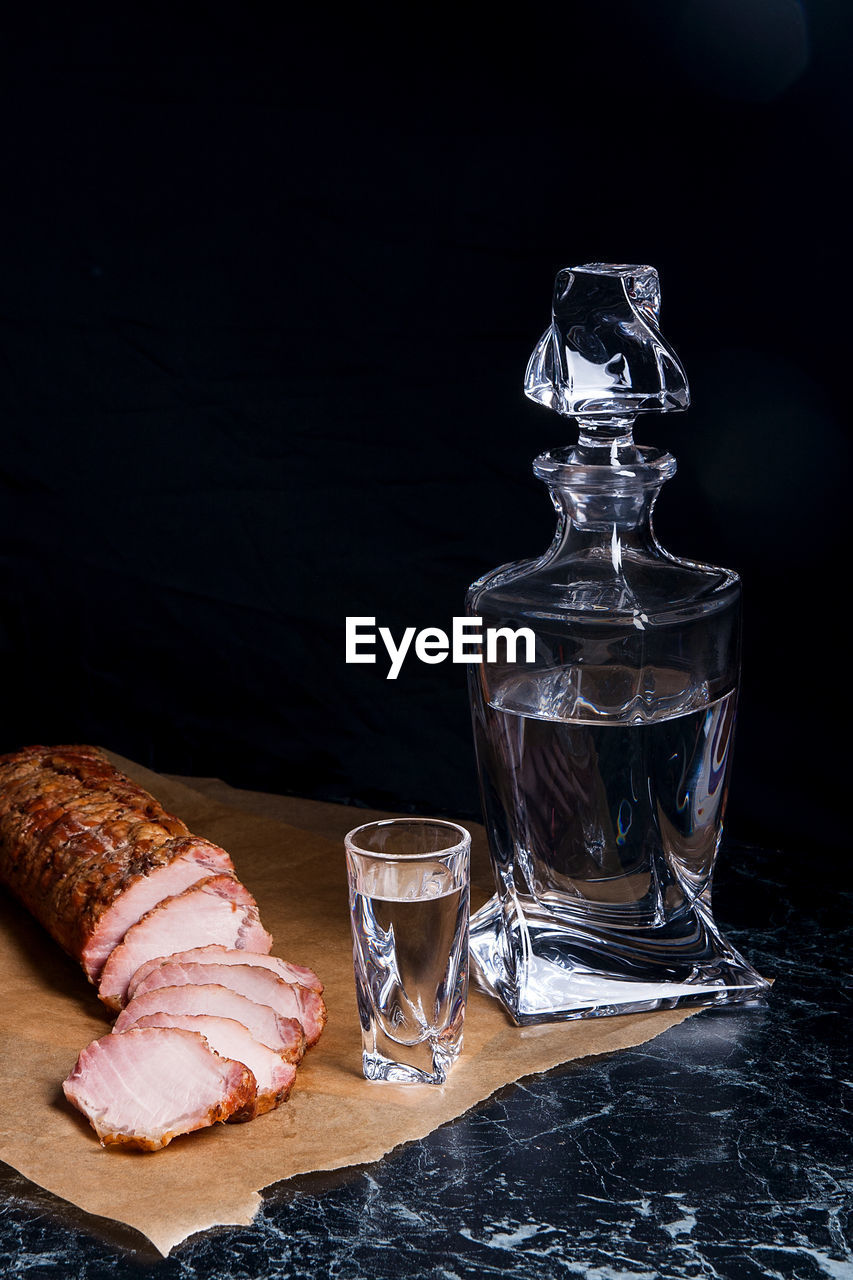 Water in glass with meat slices on marble