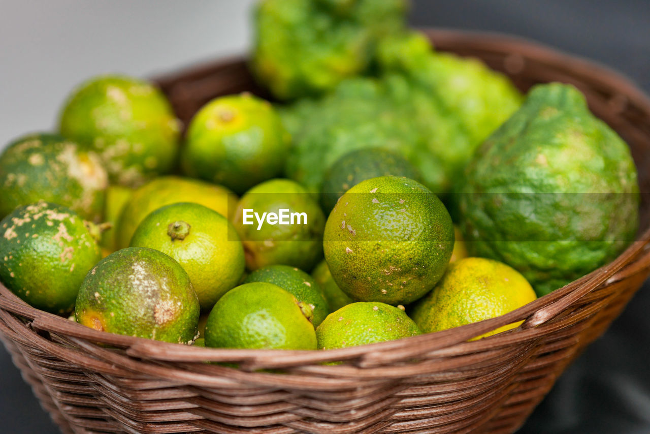 CLOSE-UP OF FRESH GREEN FRUITS IN BASKET
