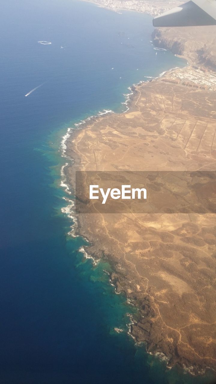 HIGH ANGLE VIEW OF BEACH AGAINST BLUE SKY