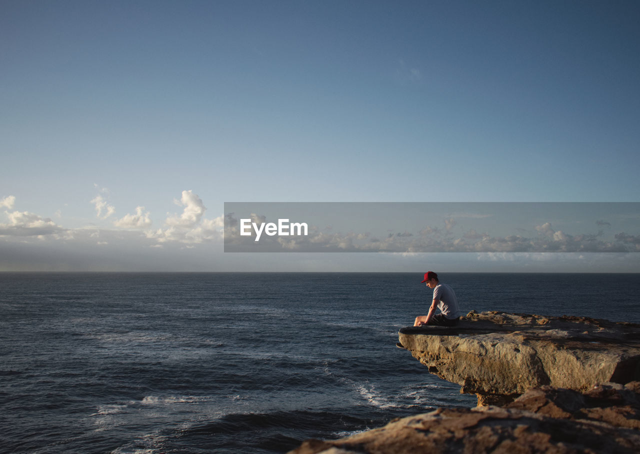 Person sitting on shore against sky