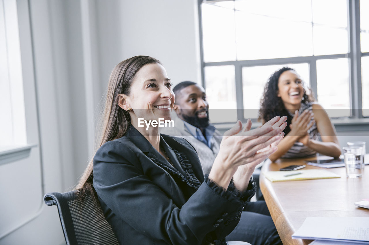 Happy business people applauding in meeting at board room