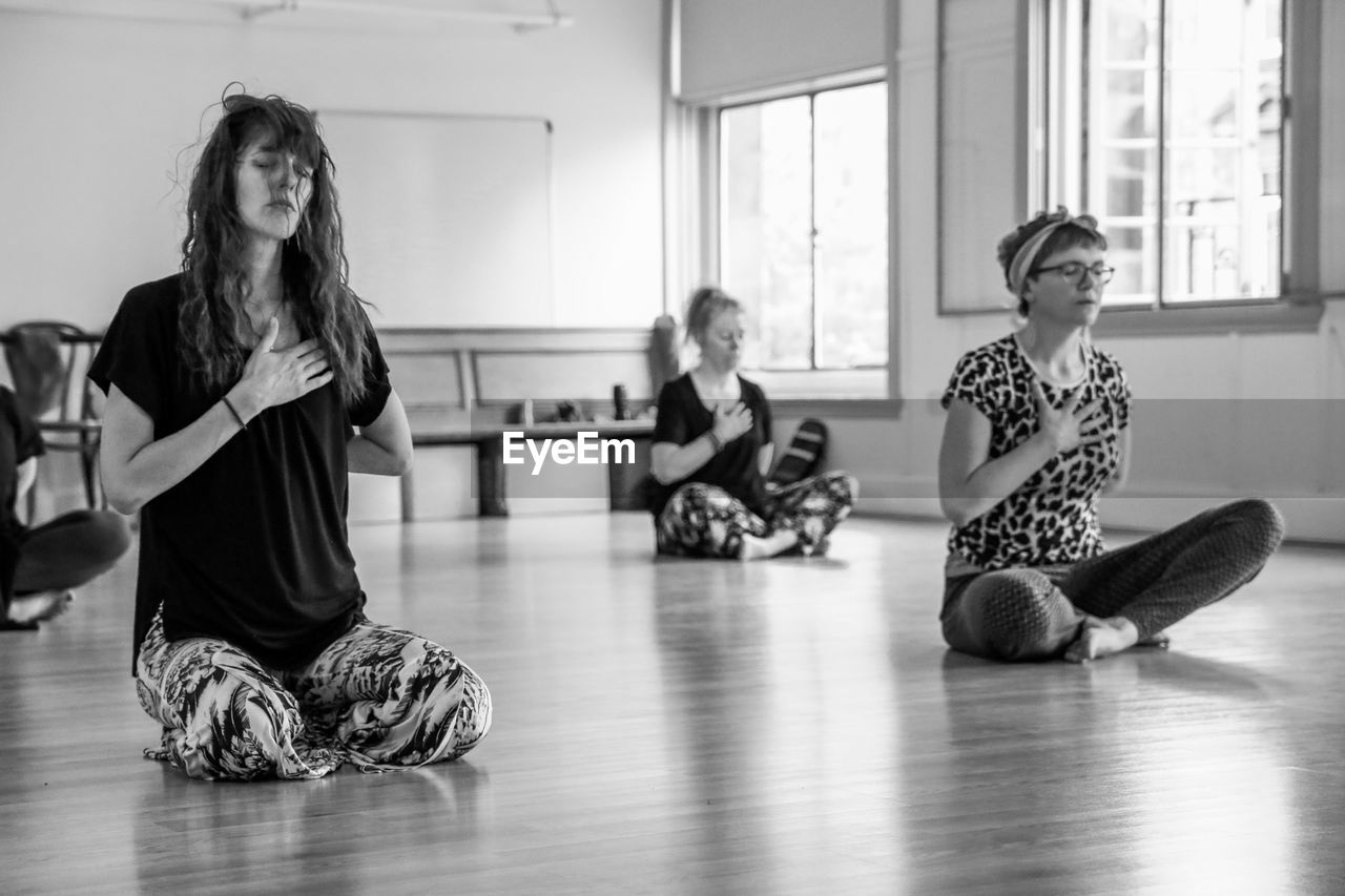 WOMAN SITTING ON WOODEN FLOOR