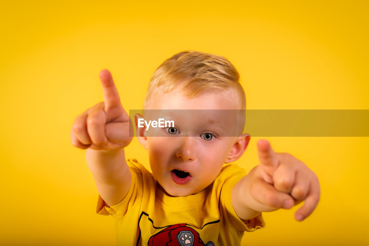 Portrait of cute boy against yellow background