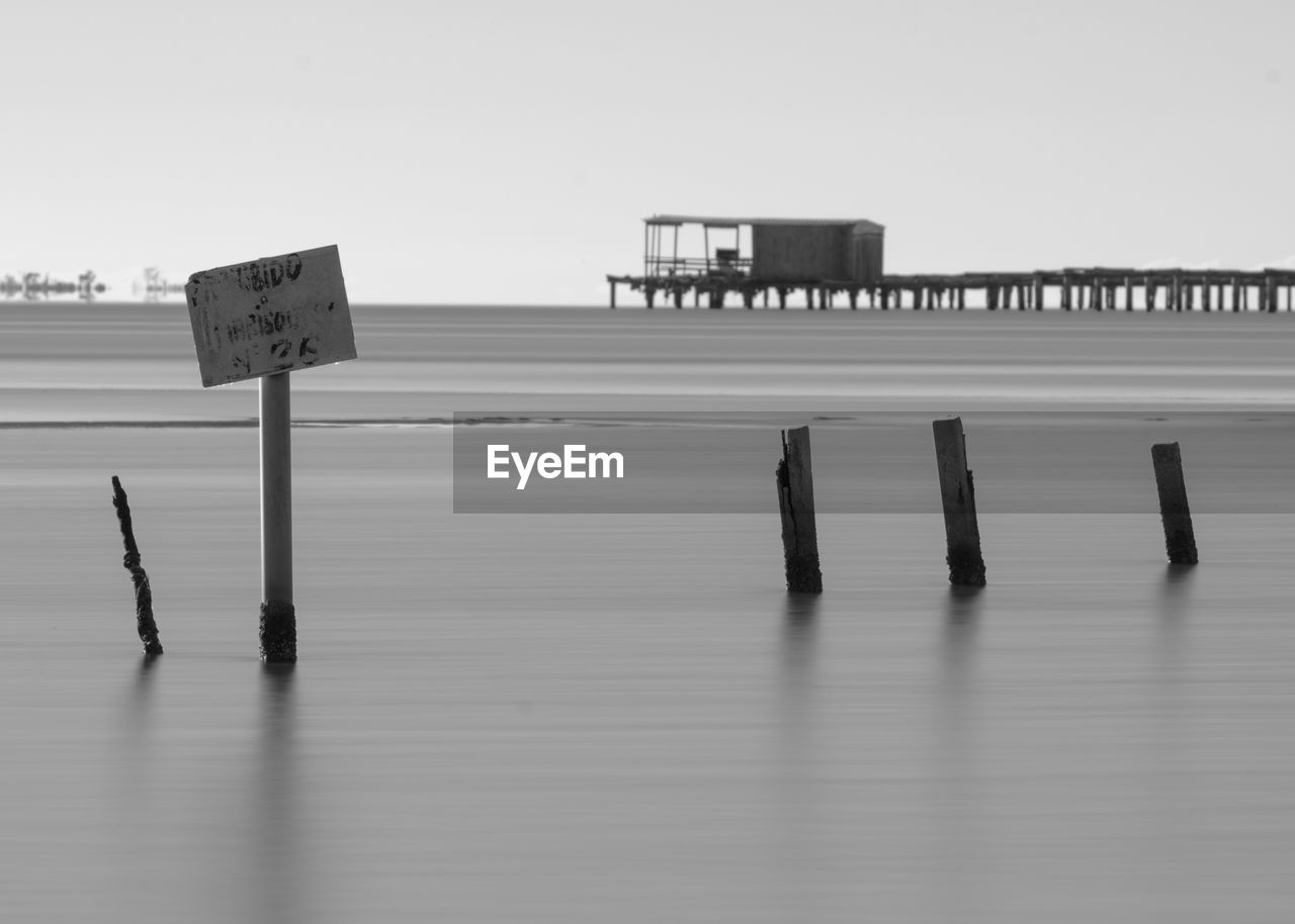 black and white, water, monochrome photography, monochrome, no people, nature, sky, wood, sign, white, communication, day, text, architecture, beach, copy space, built structure, horizon, outdoors