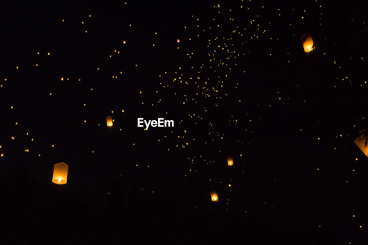 LOW ANGLE VIEW OF ILLUMINATED LIGHTS AGAINST DARK SKY