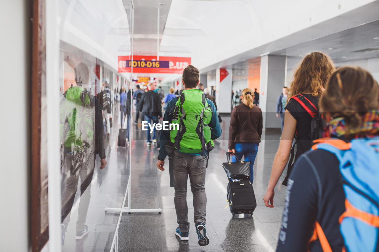 REAR VIEW OF PEOPLE STANDING IN CORRIDOR OF BUILDING