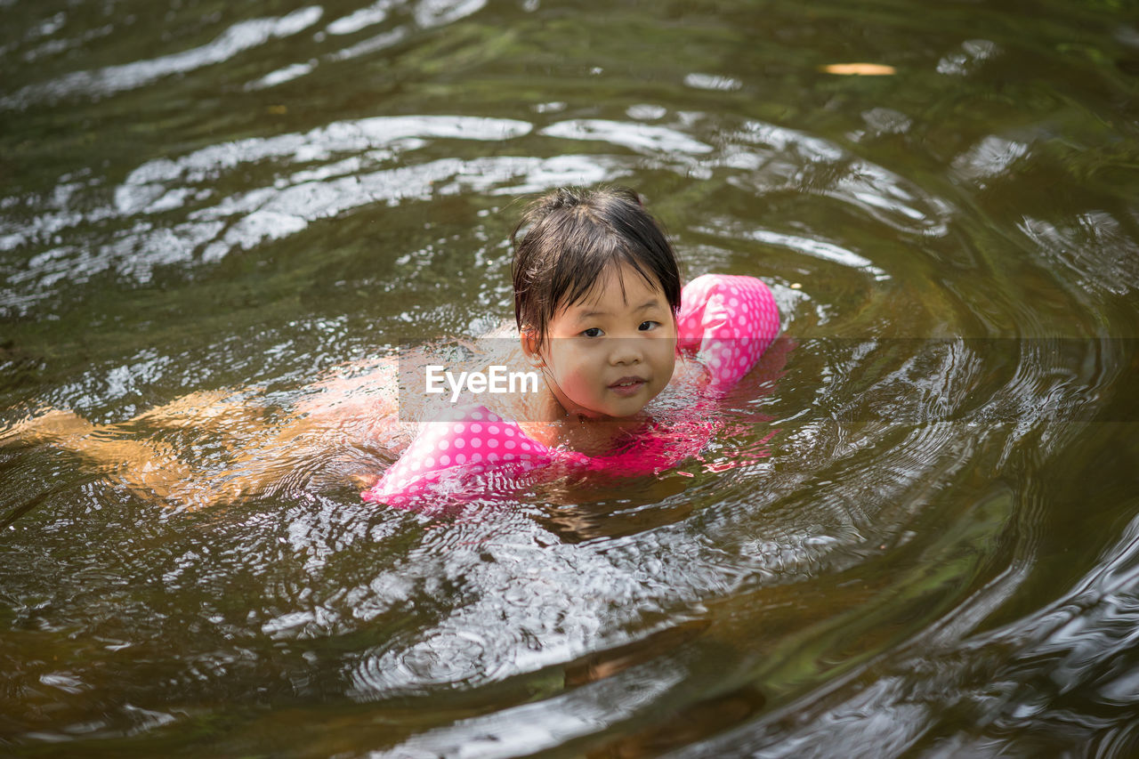 Cute girl with water wings swimming in lake