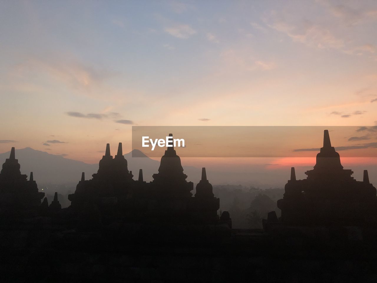 PANORAMIC VIEW OF A TEMPLE AGAINST SKY DURING SUNSET