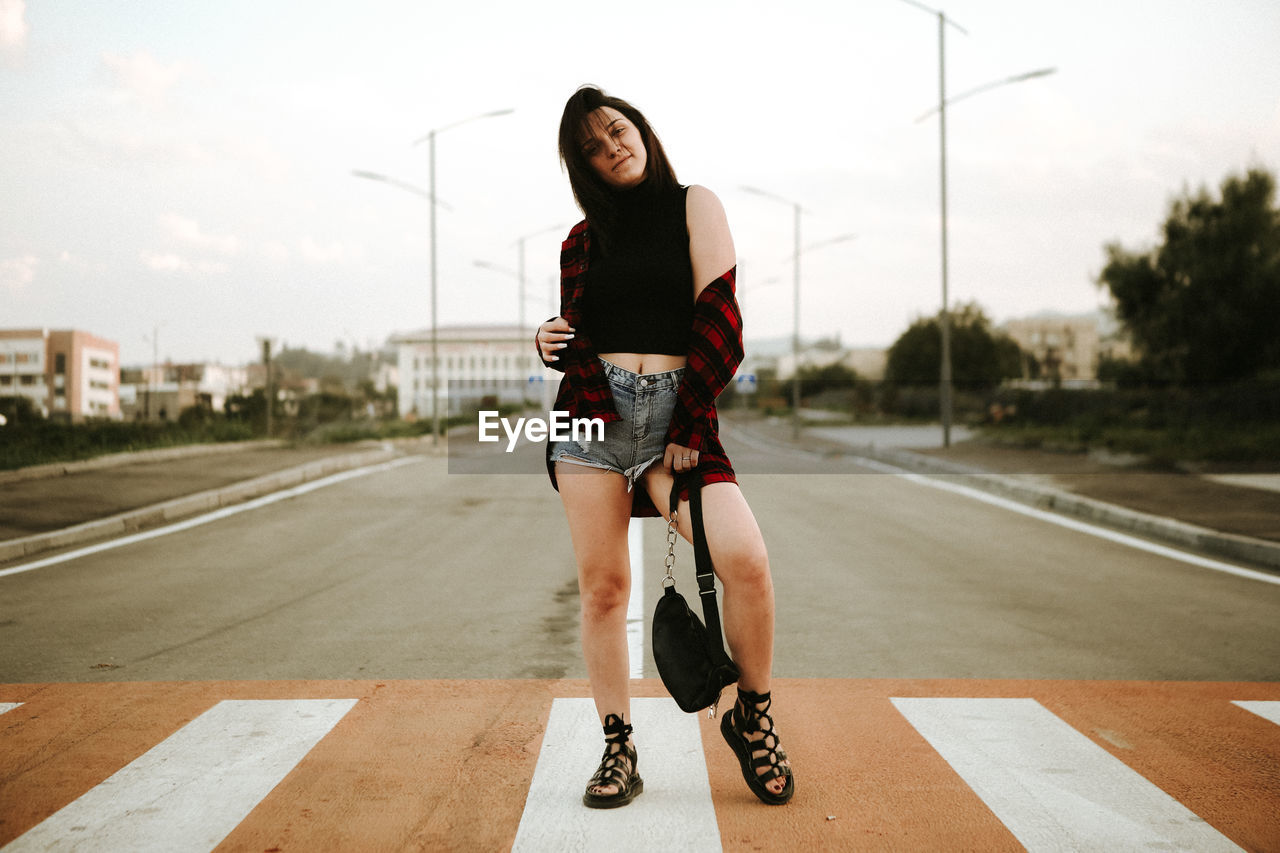 Full length of fashionable young woman on zebra crossing in city