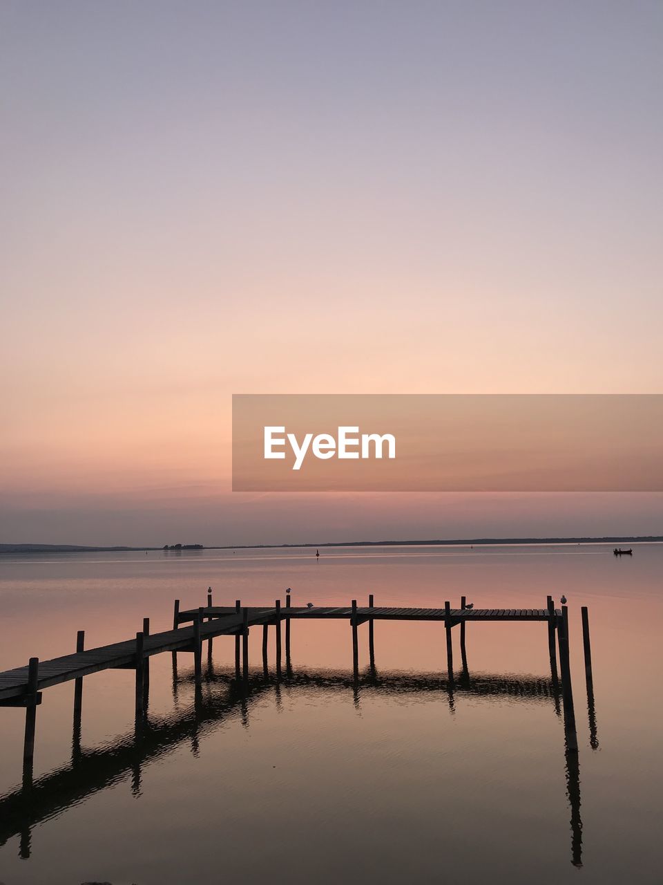 Pier over sea against sky during sunset