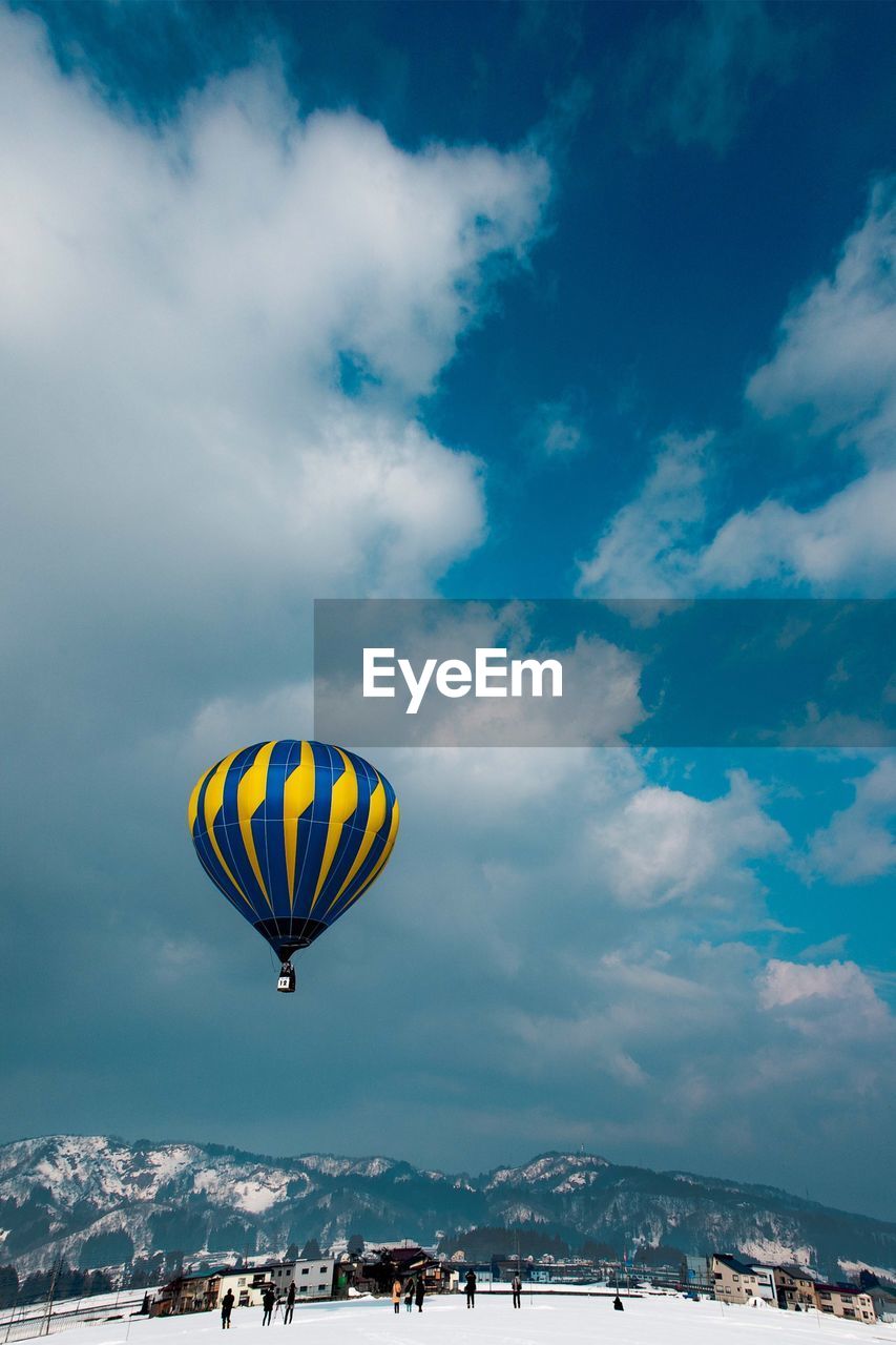 Hot air balloon flying over mountain against cloudy sky