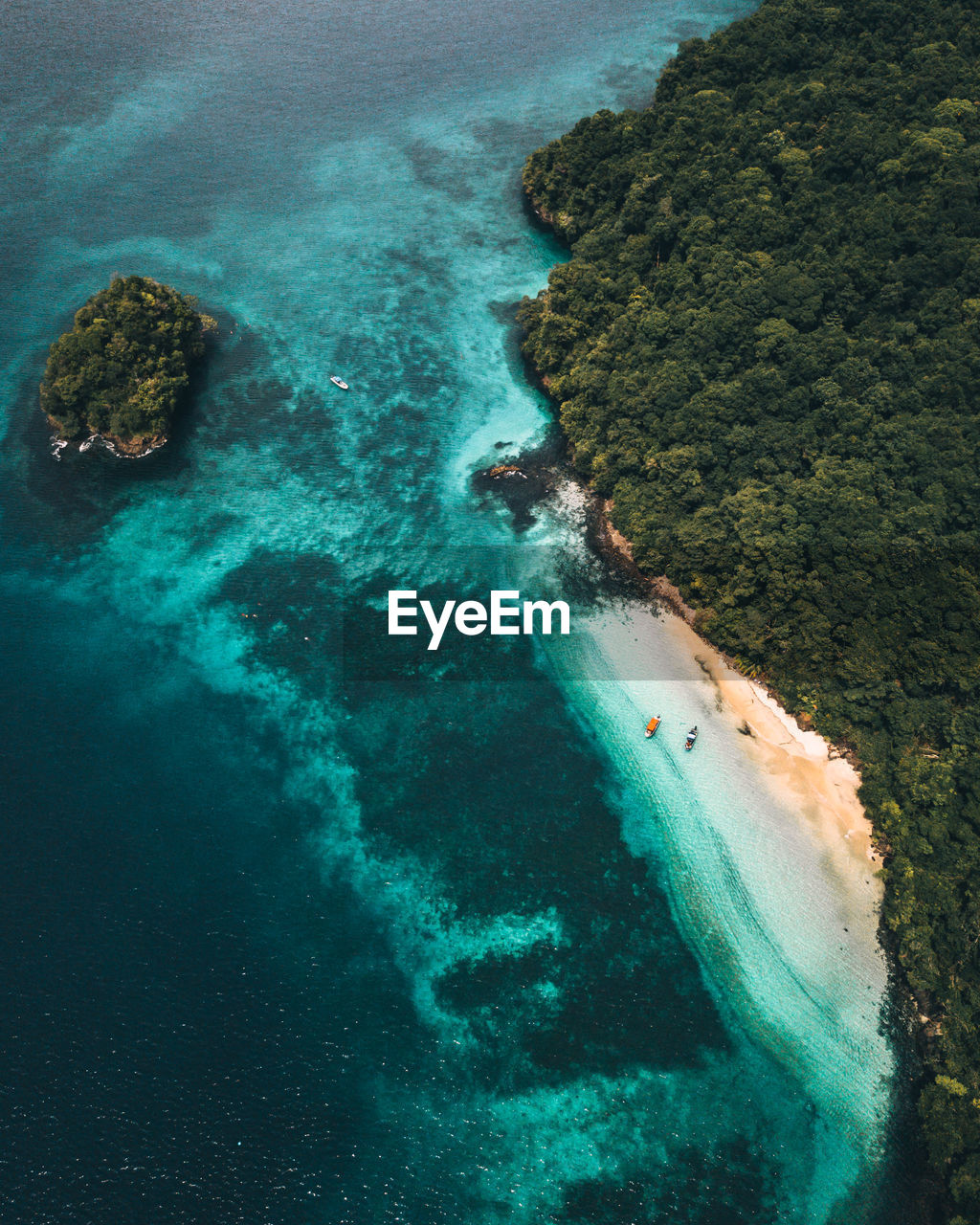 High angle view of islands covered by vegetation in with two boats in a small beach