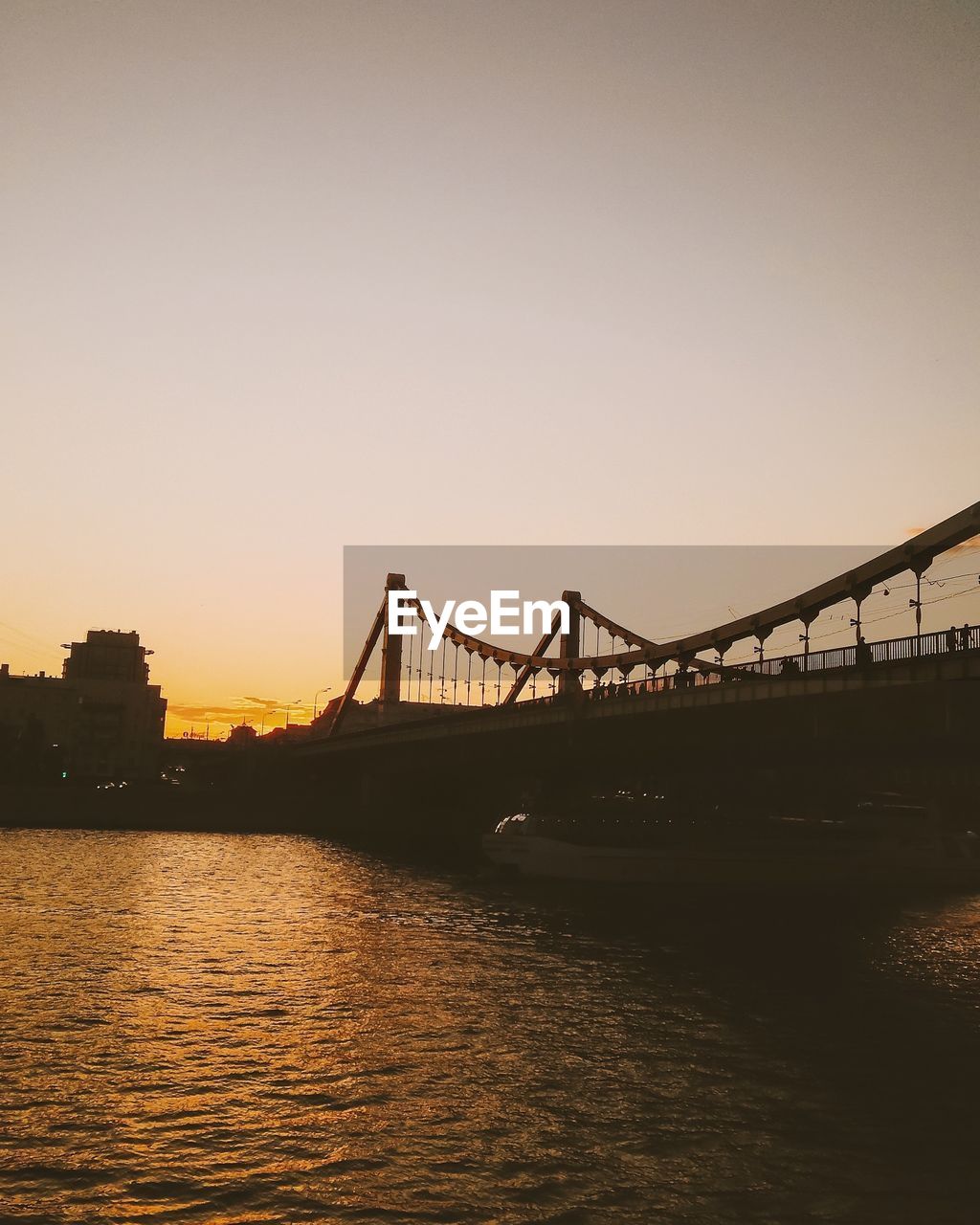 Low angle view of bridge over river against clear sky at dusk