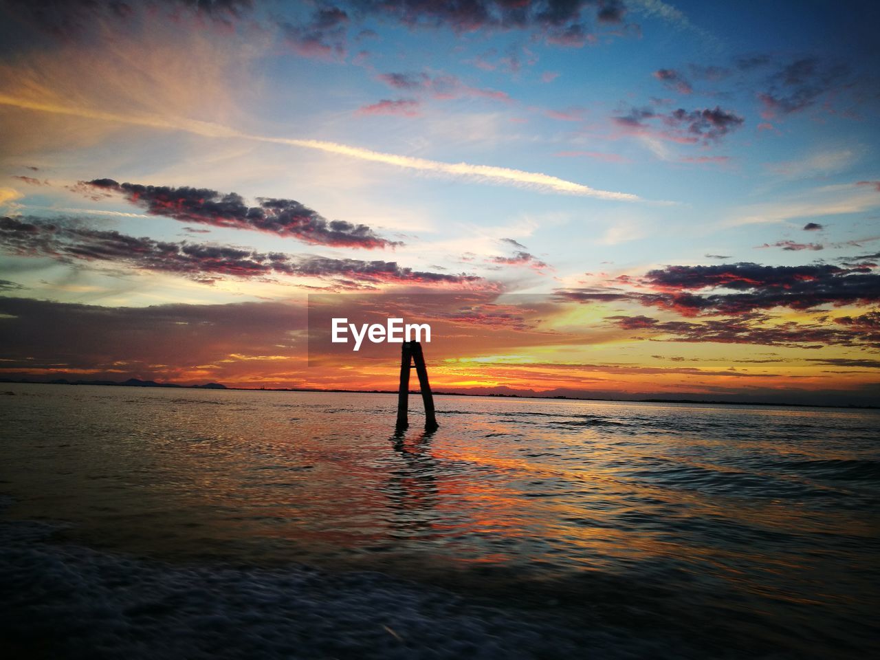 SILHOUETTE MAN STANDING ON BEACH AGAINST SKY AT SUNSET