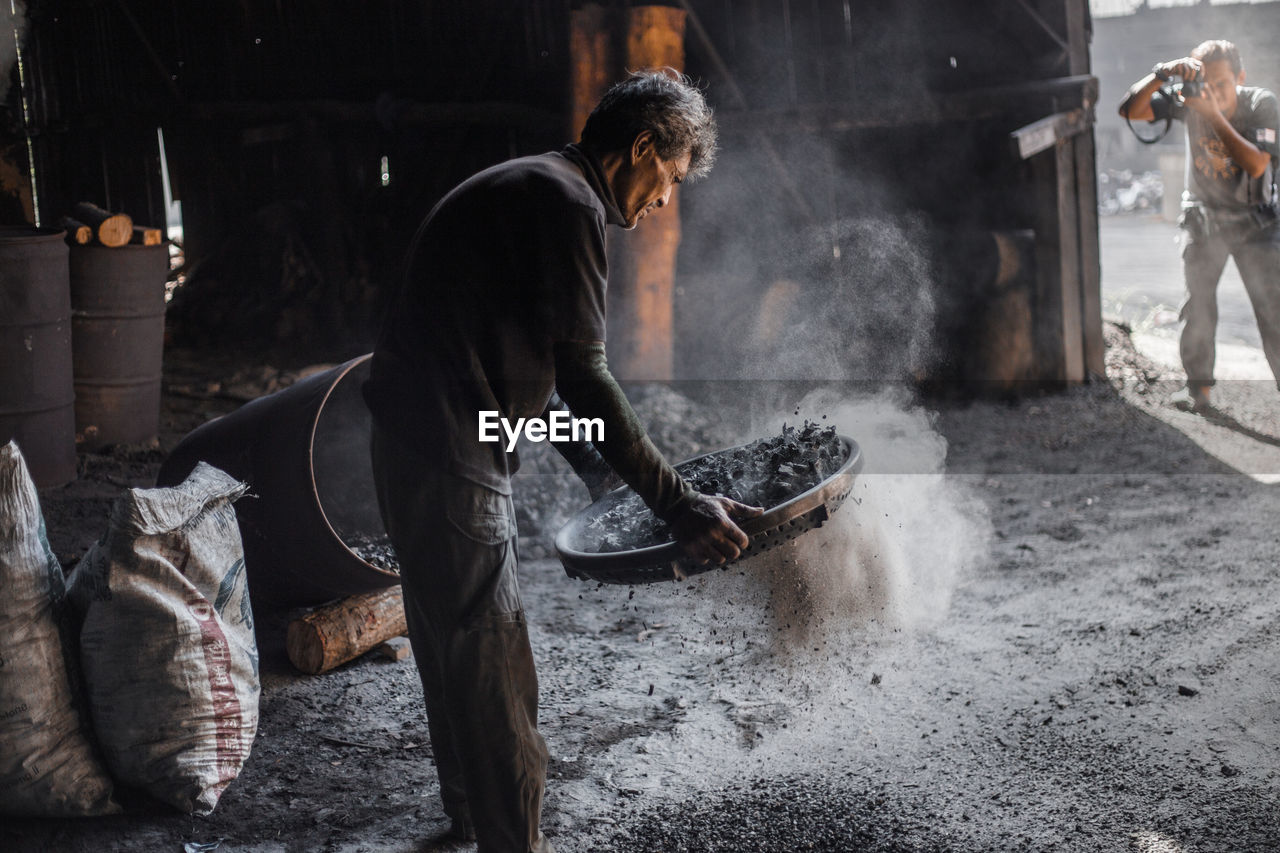 Photographer photographing worker in factory