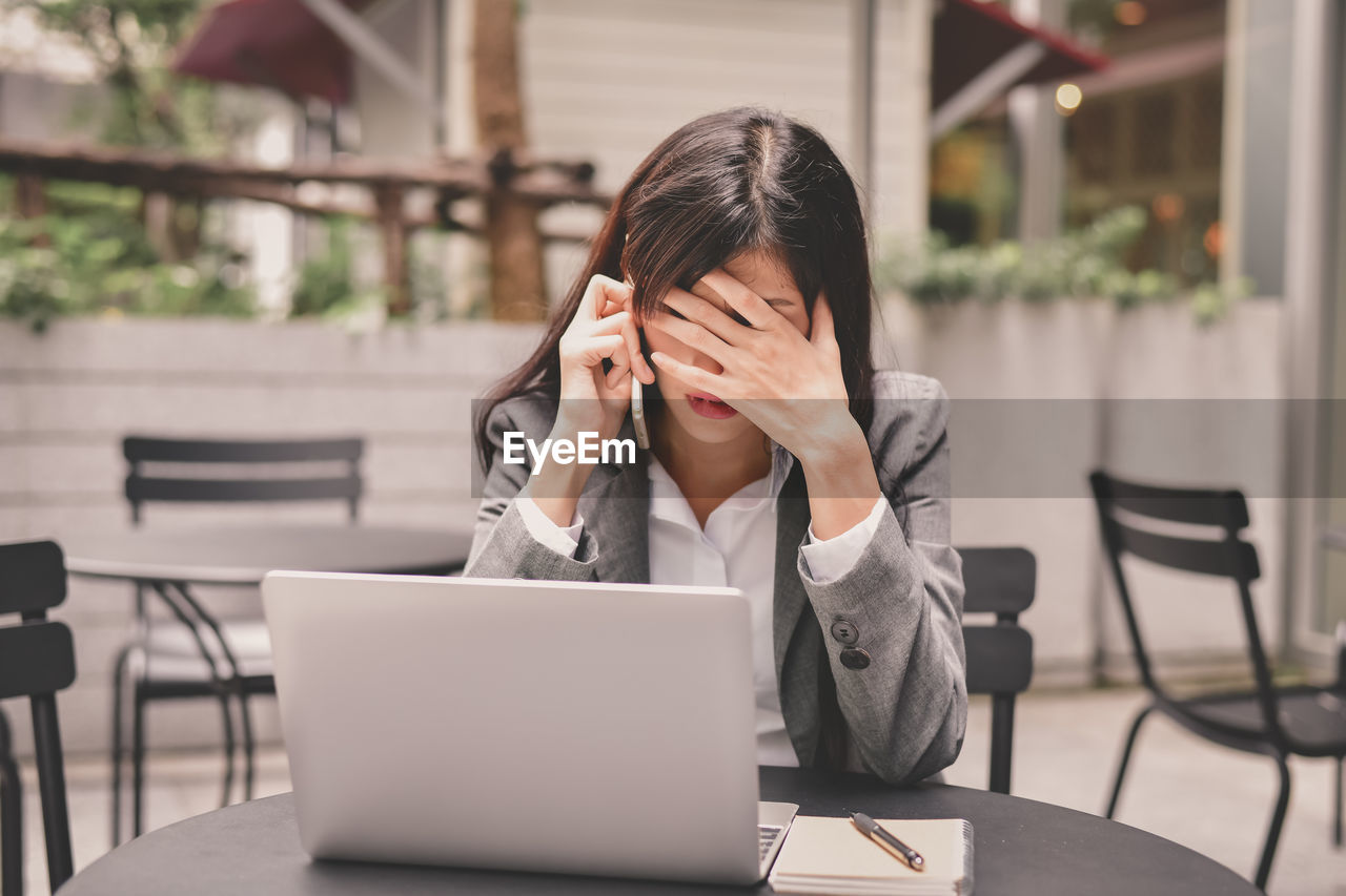 Tensed businesswoman talking on mobile phone at table in cafe