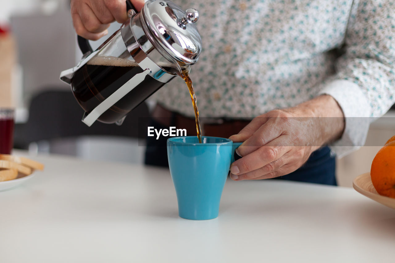 Midsection of person pouring coffee in cup