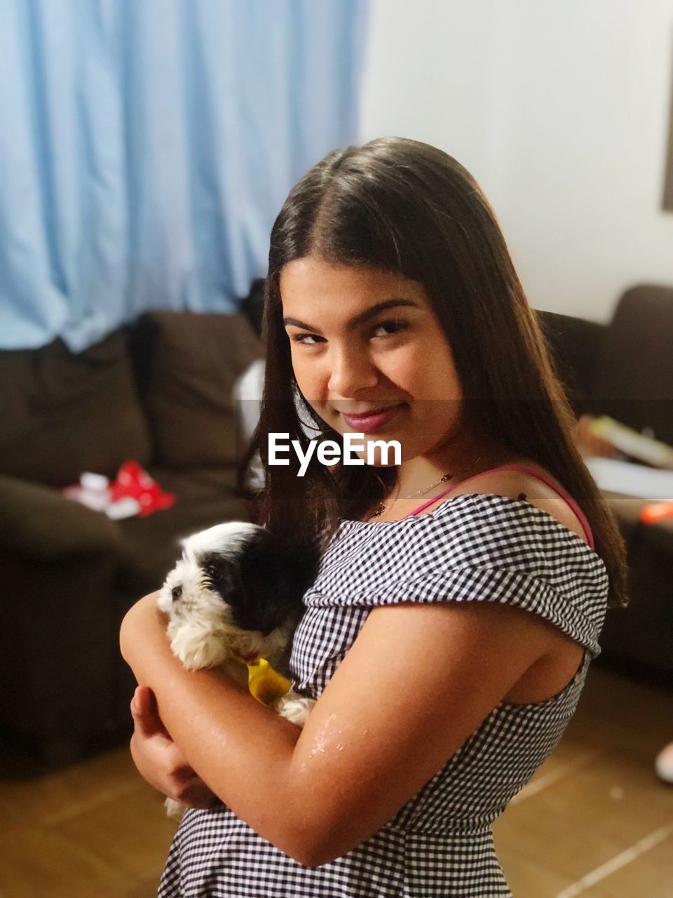 Portrait of girl holding dog while standing at home