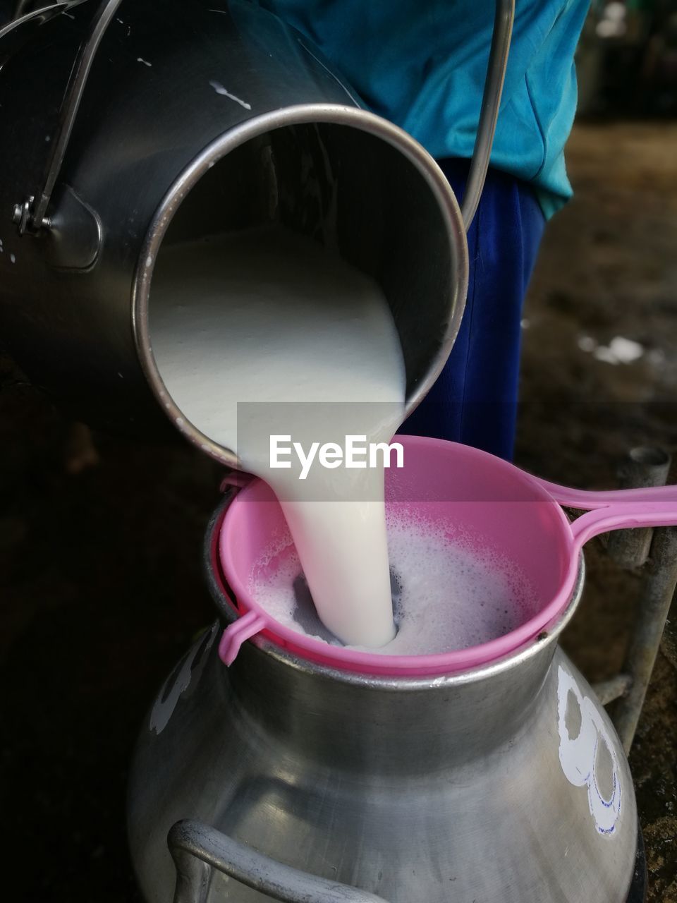 Midsection of man pouring milk from canister in container