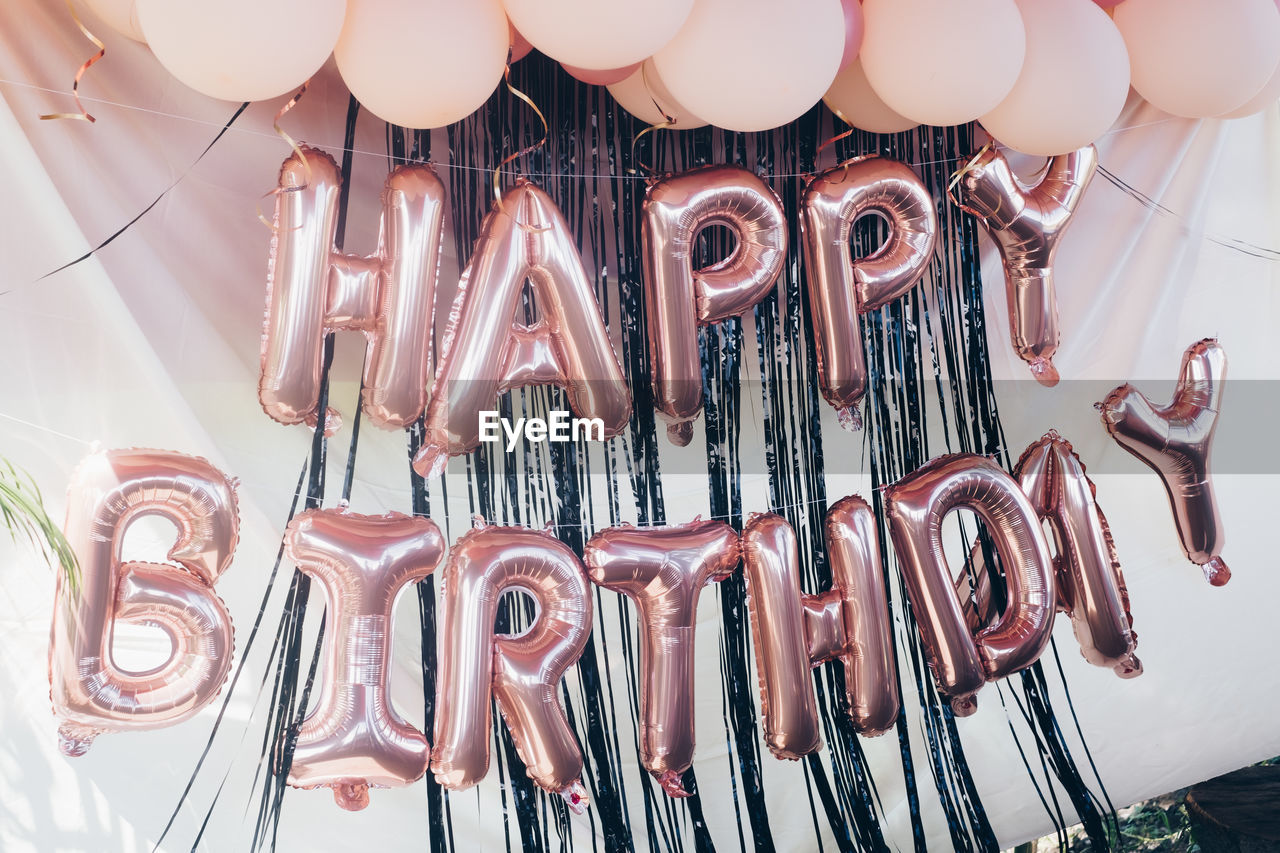 Peach pink happy birthday metallic balloons hanging on light fabric