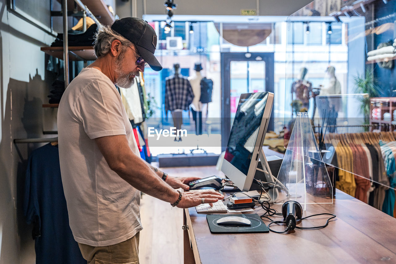 Side view of clothing store owner checking sales on computer person