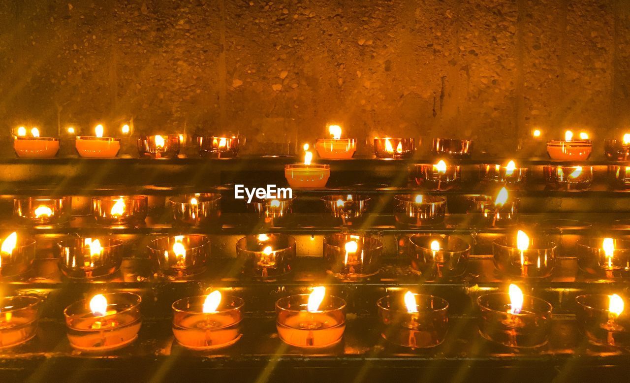 ILLUMINATED CANDLES BY BUILDING AGAINST SKY