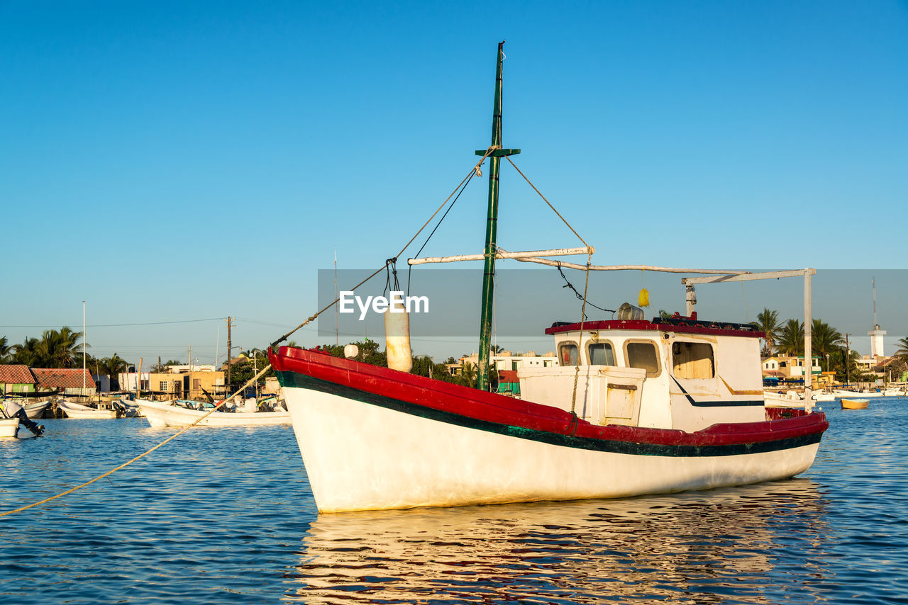 BOATS MOORED IN SEA AGAINST CLEAR BLUE SKY