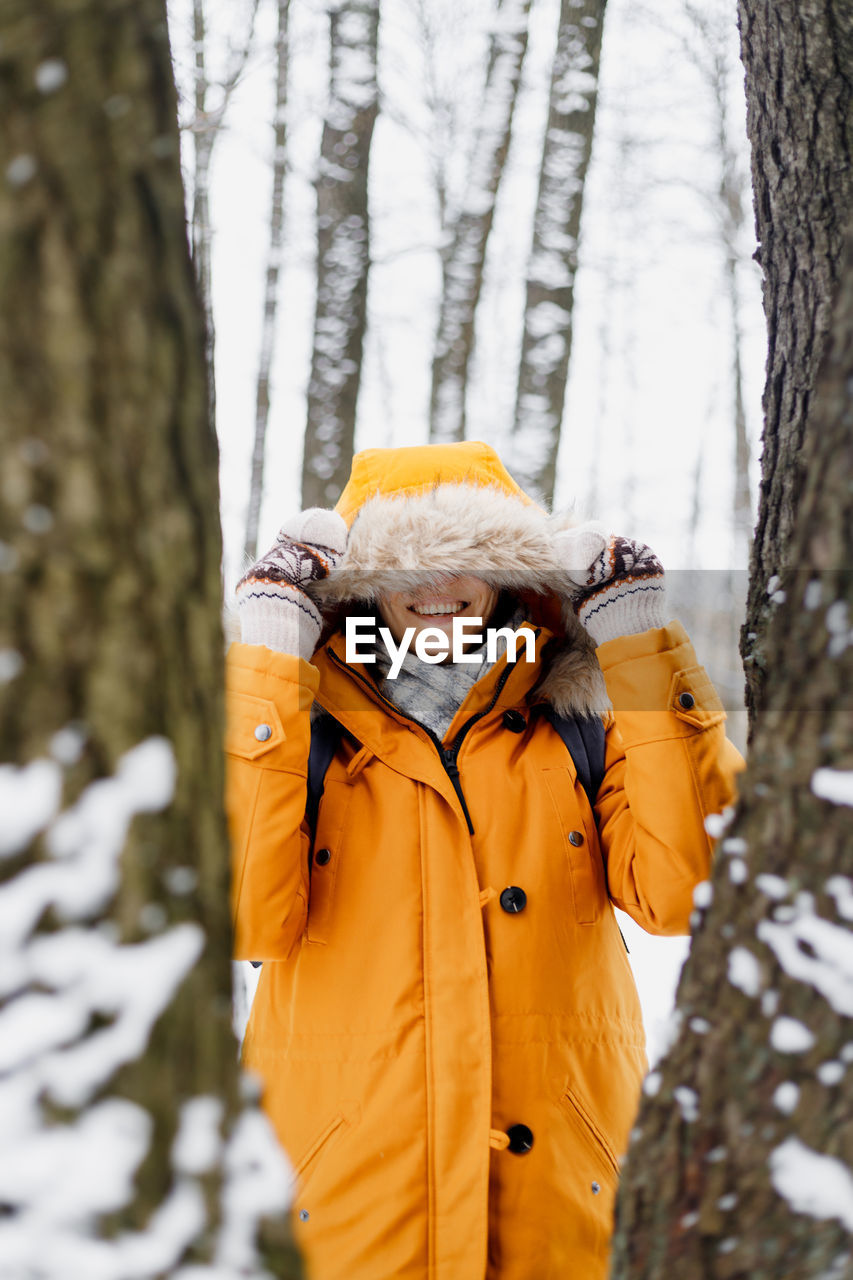 Woman standing by tree trunk during winter