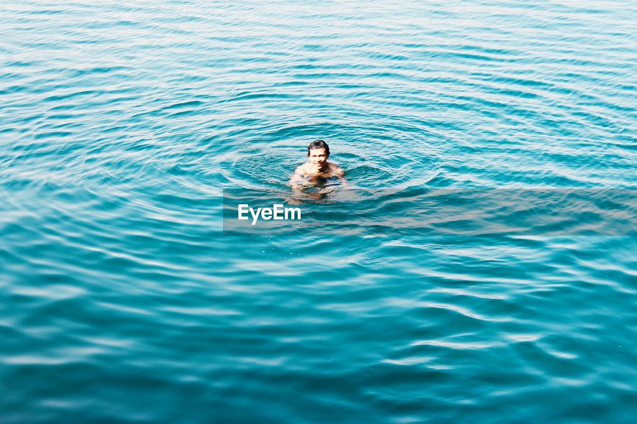 HIGH ANGLE VIEW PORTRAIT OF MAN SWIMMING IN SEA