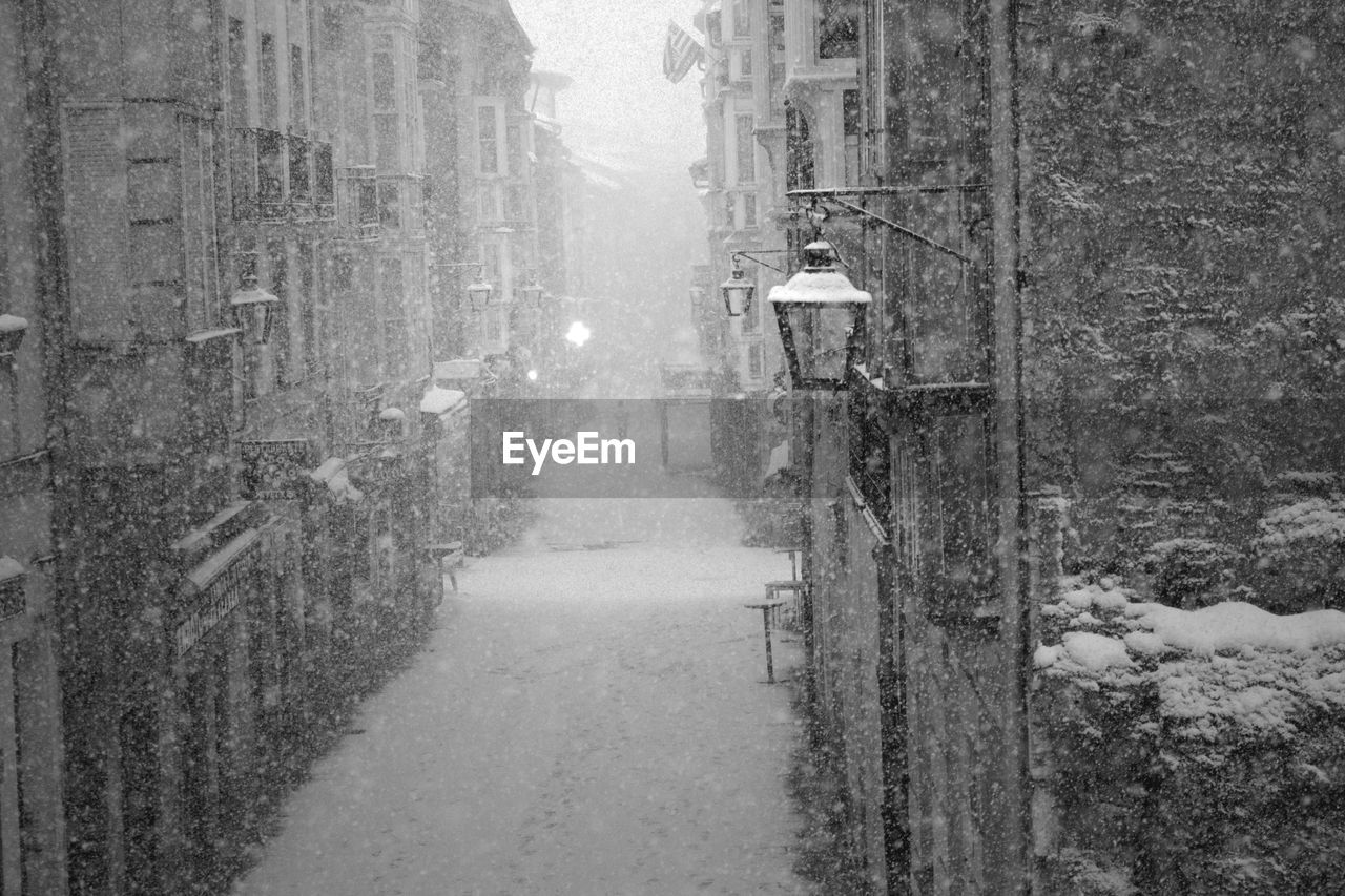 Snow covered road along buildings