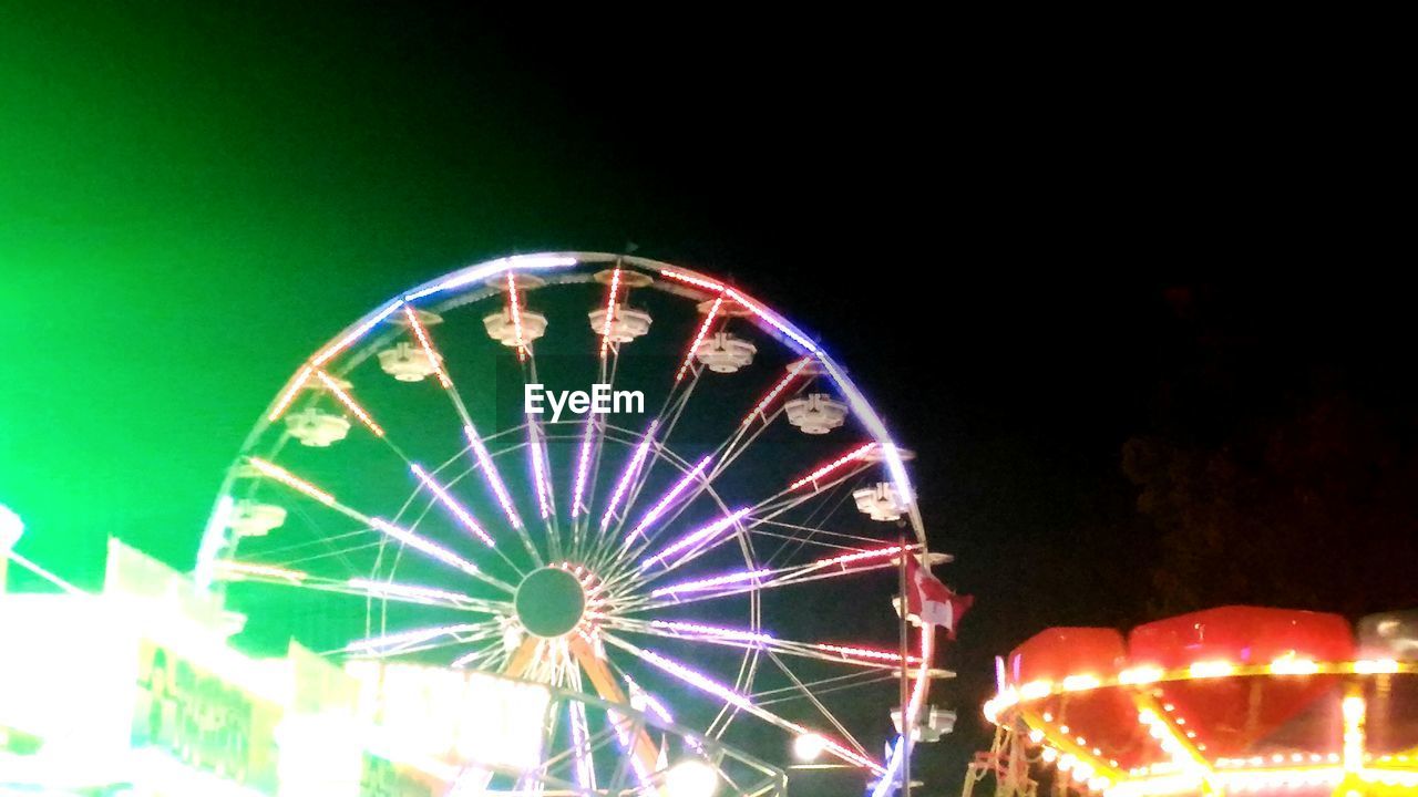 LOW ANGLE VIEW OF FERRIS WHEEL AGAINST ILLUMINATED SKY