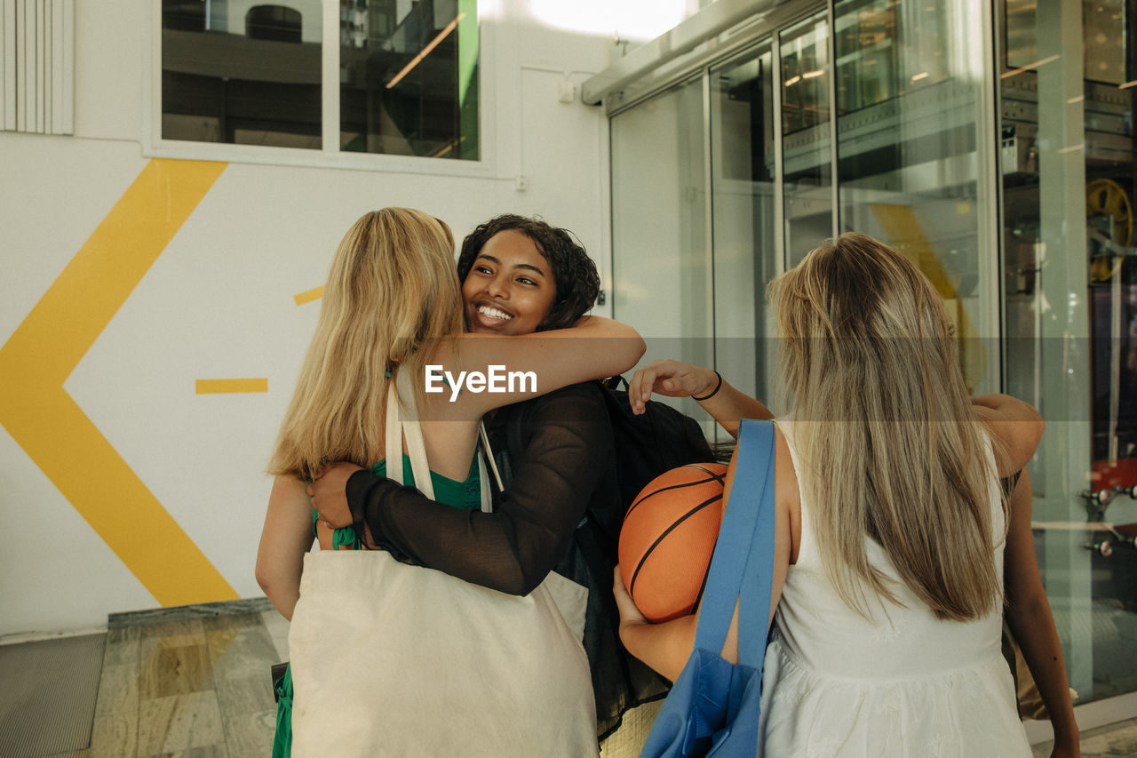 Smiling teenage girl hugging female friend in mall