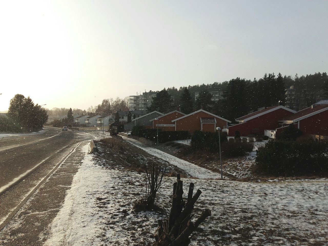 Road by houses against clear sky during winter